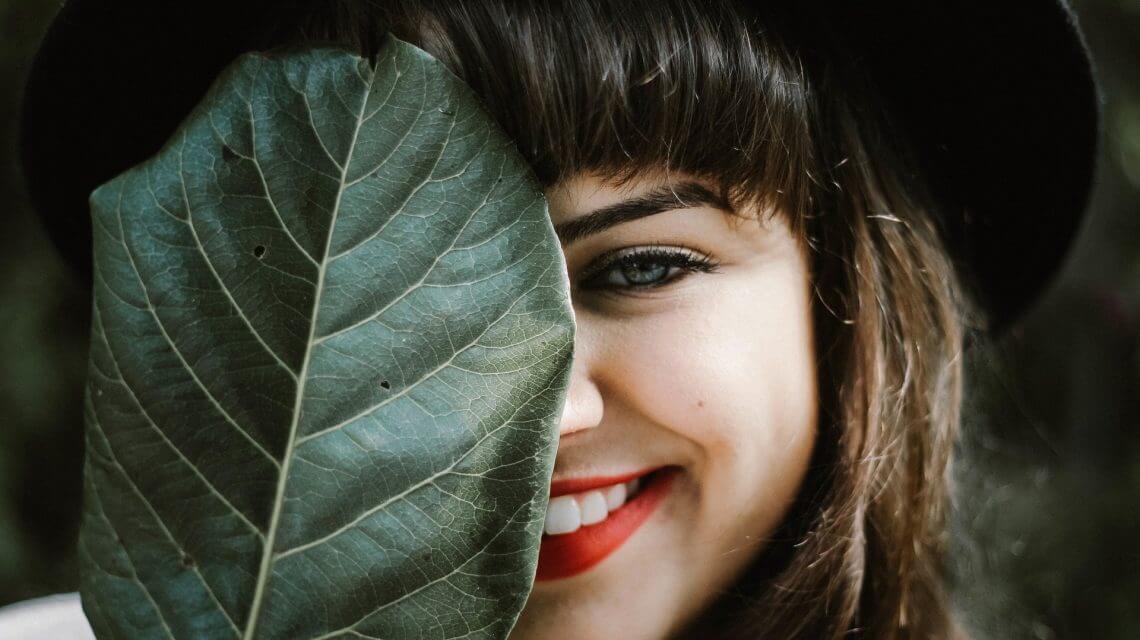Girl Smiling Behind Leaf